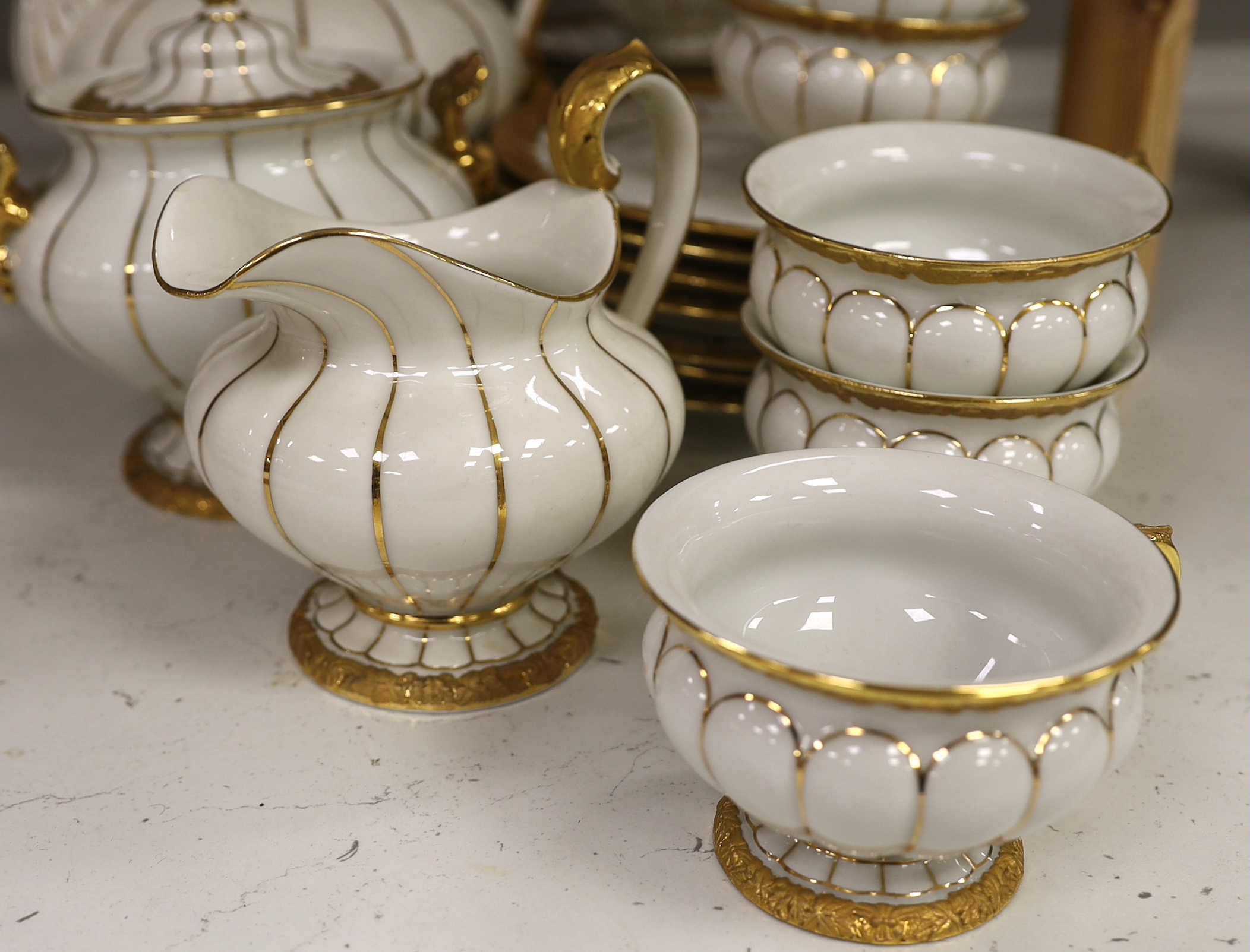 A Meissen gilt and white glazed porcelain tea service, mid 20th century, comprising a teapot, coffee pot, sugar bowl, side plates and seven cups and saucers, coffee pot 28cm